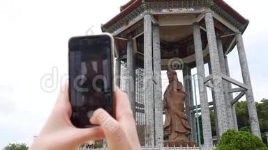 女用智能手机拍摄观音观音或佛寺观音雕像。 访问精神